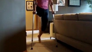 Mulher amputada descalça pratica uso de muletas + um andador